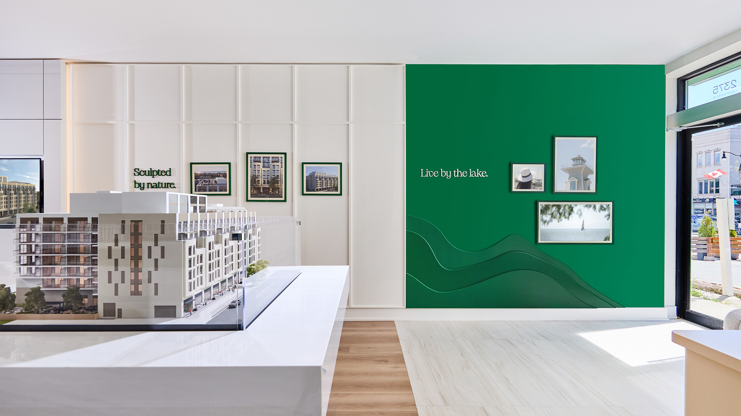 Interior view of Claystone sales office featuring a green feature wall with 3D brand pattern and signage.